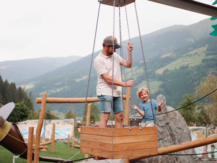 Habachklause-Abenteuerspielplatz mit schwebendem Korb Vater ist mit seinem Sohn am Spielplatz im schwebenden Korb