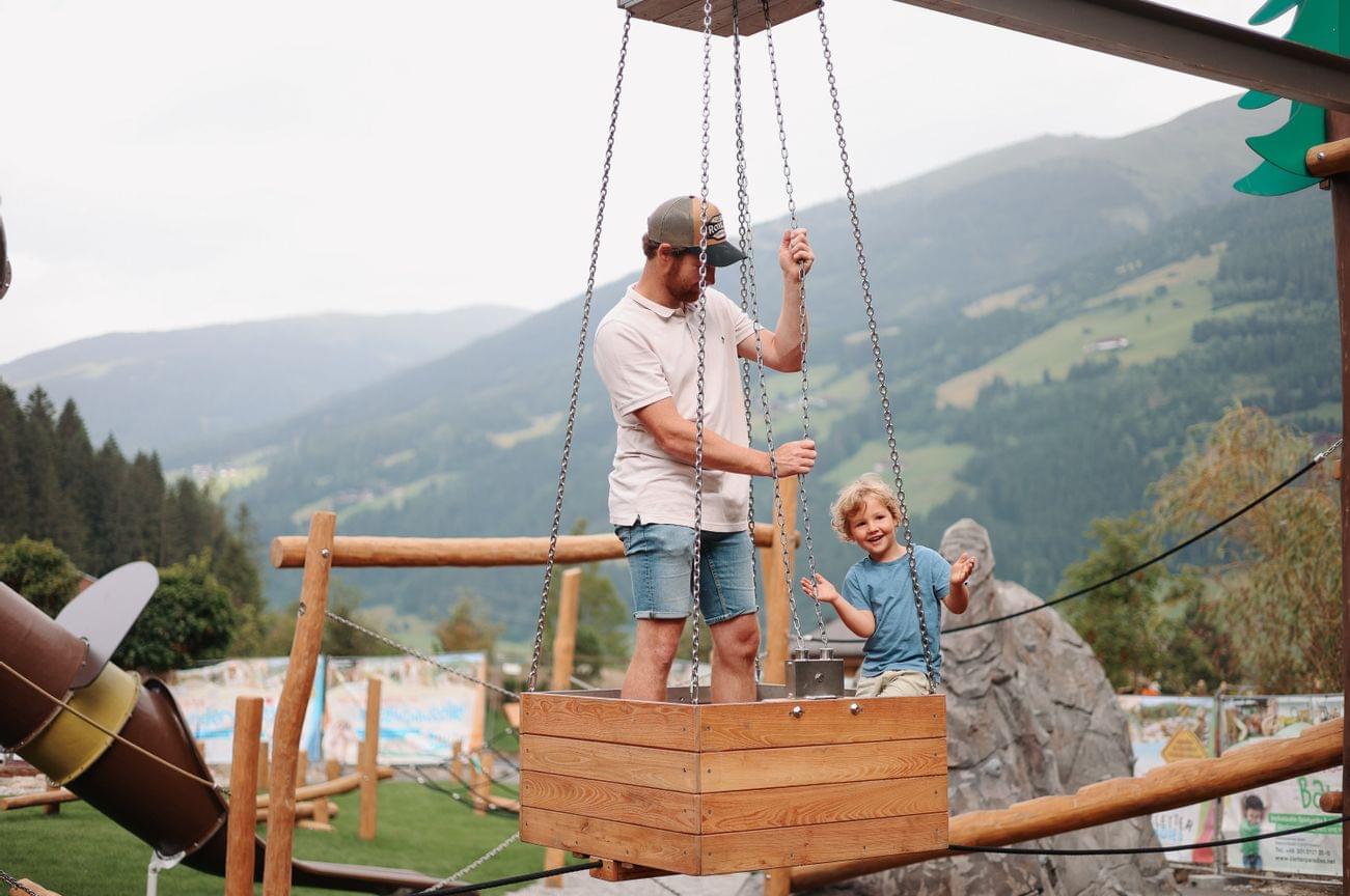 Vater ist mit seinem Sohn am Spielplatz im schwebenden Korb