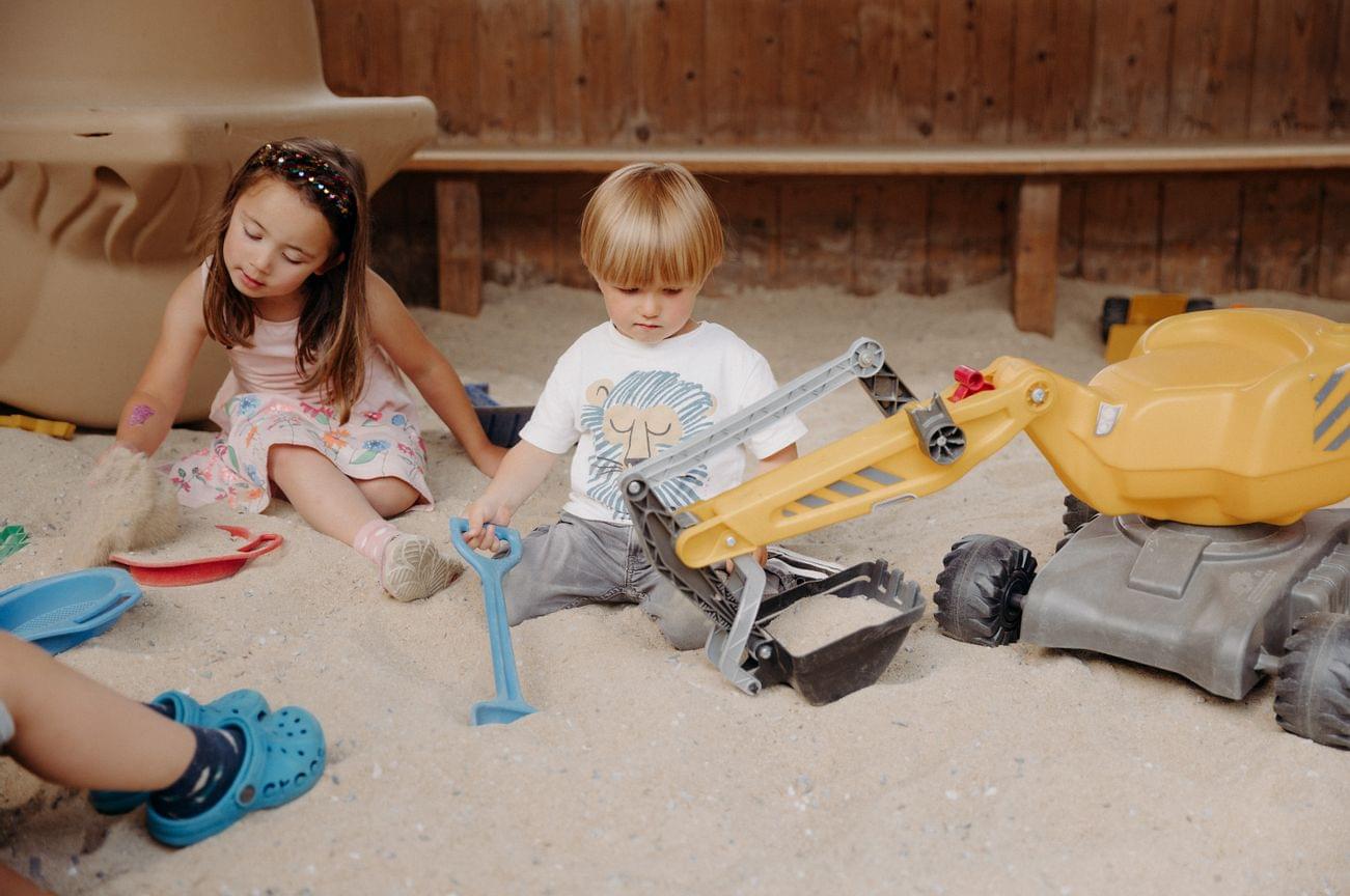 Kinder spielen in der riesengroßen überdachten Sandkiste mit Spielsachen
